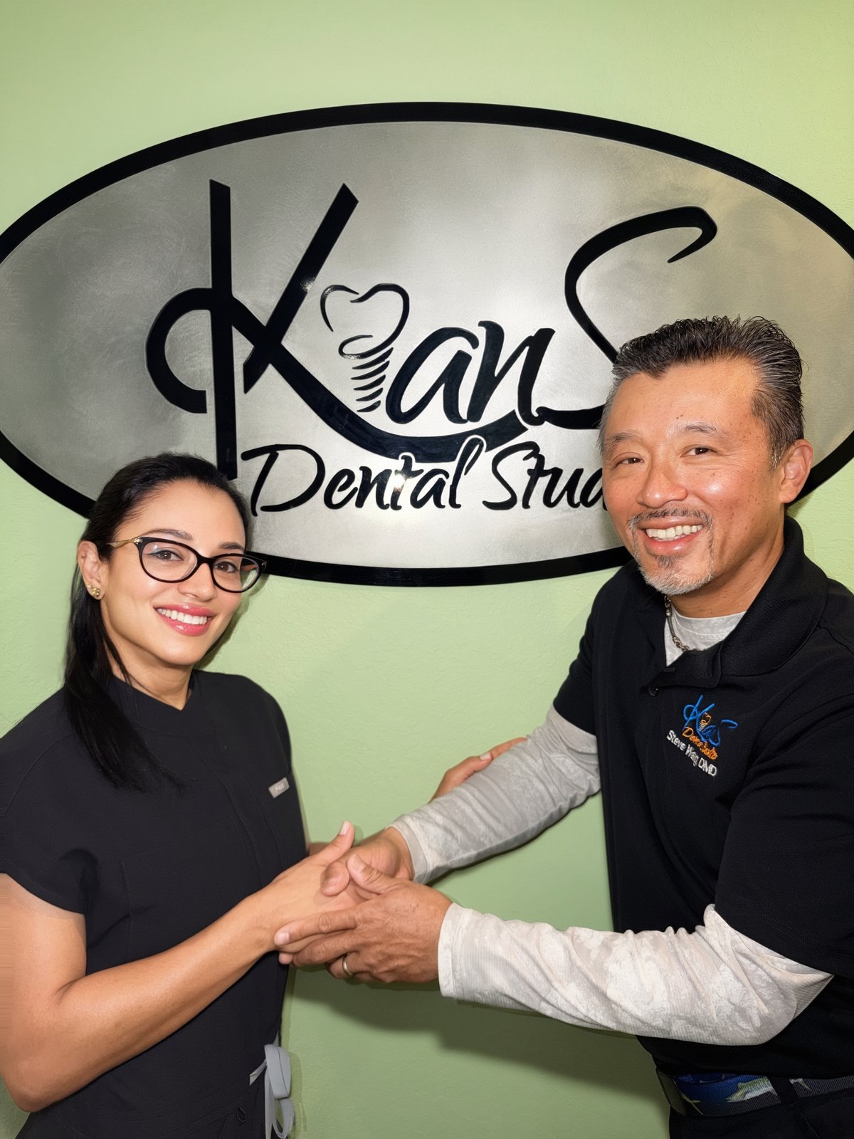 Dr. Steve Wang shaking hands with Dr. Yeritza Jaquez in front of the Kians Dental Studio sign